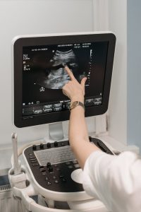 A medical professional analyzing an ultrasound image on a monitor in a clinical setting.